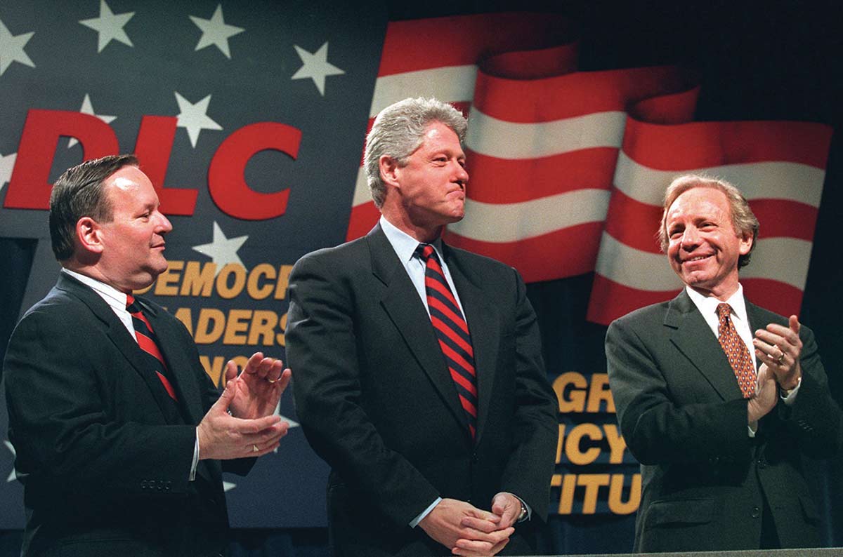 Bill Clinton is applauded by Al From, left, and Senator Joseph Lieberman, right, before to addressing the DLC in Washington in 1995.